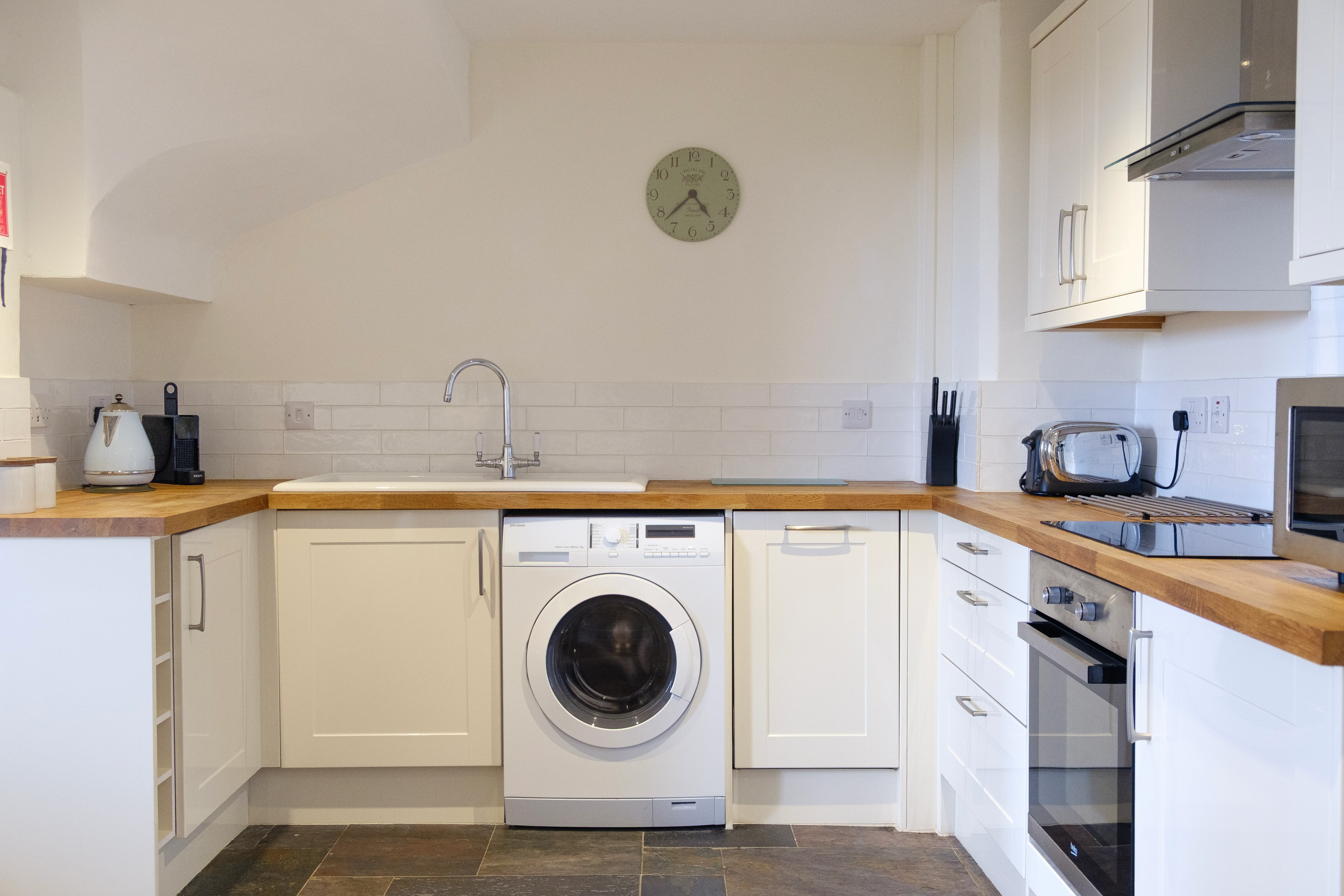 A clean, modern kitchen with white cabinets and wooden worktops